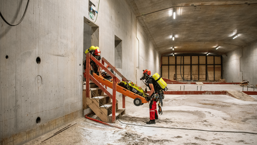 Twee brandweermannen evacueren een slachtoffer op een brancard langs een trap in de tunnel